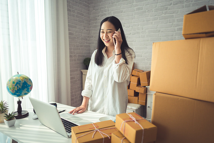 Business woman on the phone in office surrounded by parcels .